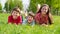 Three smiling kids lying together on green grass