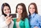 Three smiling teenage girls taking selfie with smartphone camera