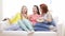 Three smiling teenage girls watching tv at home