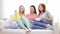 Three smiling teenage girls watching tv at home