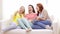 Three smiling teenage girls watching tv at home