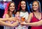 Three smiling women with cocktails in club