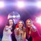 Three smiling women dancing and singing karaoke