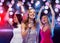 Three smiling women dancing and singing karaoke