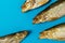 Three smoked fish with their mouths open in front of one fish on a blue background. The concept of bullying, assault, depression,