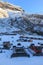 Three snowcat stand at the foot of the ski resort. Nearby parking for cars, equipment rentals and souvenir sales. In the