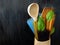 Three sorts of spaghetti, wooden spoon and a notebook decorated with basil leaves on a dark background.