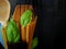 Three sorts of spaghetti, wooden spoon and a notebook decorated with basil leaves on a dark background