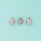 Three sparkly silver Christmas baubles  on a blue green background, with copy space