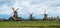 Three spinning Dutch windmills from across farmland in Zaase Schans  Netherlands