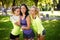 Three sportive female friends at the park outdoors make selfie on a phone with a stick, smiling.