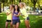 Three sportive female friends at the park outdoors make selfie on a phone with a stick, smiling.