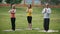 Three sportsmen performs yoga exercise outdoors in a green park