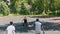 Three sportsmen playing basketball on the court outdoors - man in black uniform throwing the ball