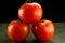 Three stacked tomatoes on black gray background