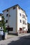 Three storey newly built small suburban apartment building with concrete driveway and metal fence next to paved road