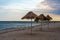 Three straw beach umbrellas on an empty seashore on a clear day