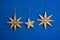 Three straw stars on blue wall, christmas decoration.