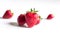 Three strawberries close-up on a light background. Main strawberry in focus and others in the background in strong defocus