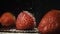 Three strawberries in a row on a black table. Slow mo