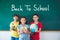 Three student smiling in front of chalkboard