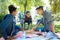 Three students eating pizza while having picnic in nature