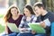 Three students learning online in a park