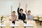 Three students raised their hands together in the classroom.