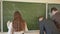 Three students write on the blackboard mathematical formulas in the classroom. Russian school.