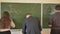 Three students write on the blackboard mathematical formulas in the classroom. Russian school.