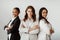 Three successful multicultural businesswomen standing with arms crossed and smiling at camera, posing in office