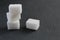 Three sugar cubes are stacked on top of each other or in a pyramid on a white gray and black background with space for inserting t