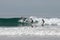 The three surfers rolls on a surfboard on a wave in the Pacific Ocean