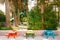 Three tables with benches of different colors. Street furniture in the park. Red, green-yellow and blue tables with