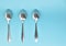 Three tablespoons lying in a row upside down on a light background