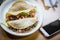 Three tacos on a plate next to a cell phone