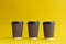 Three takeaway brown paper coffee cups with black plastic covers