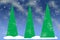 Three tall abstract Christmas Trees on snow drifts at dusk