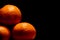 Three tangerine on a black background with blank space in contrast light