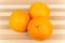 Three tangerine on striped bamboo Board