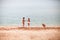 Three tanned Caucasian children on beach with yellow sand, summ