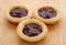 Three tasty jam tarts on a wooden table