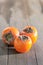 Three tasty persimmons on wooden table