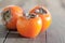 Three tasty persimmons on wooden table