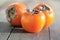 Three tasty persimmons on wooden table