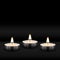 Three tealight burning realistic candles on black background