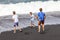 Three teen boys have fun at a black volcanic beach