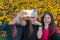 Three teen girls take a selfie on Phone on a sunny day and laugh. Girls are showing victory sign with their fingers