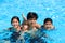 Three teen siblings smiling together in pool