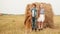 Three teenagers standing near haystack in field and looking at sky